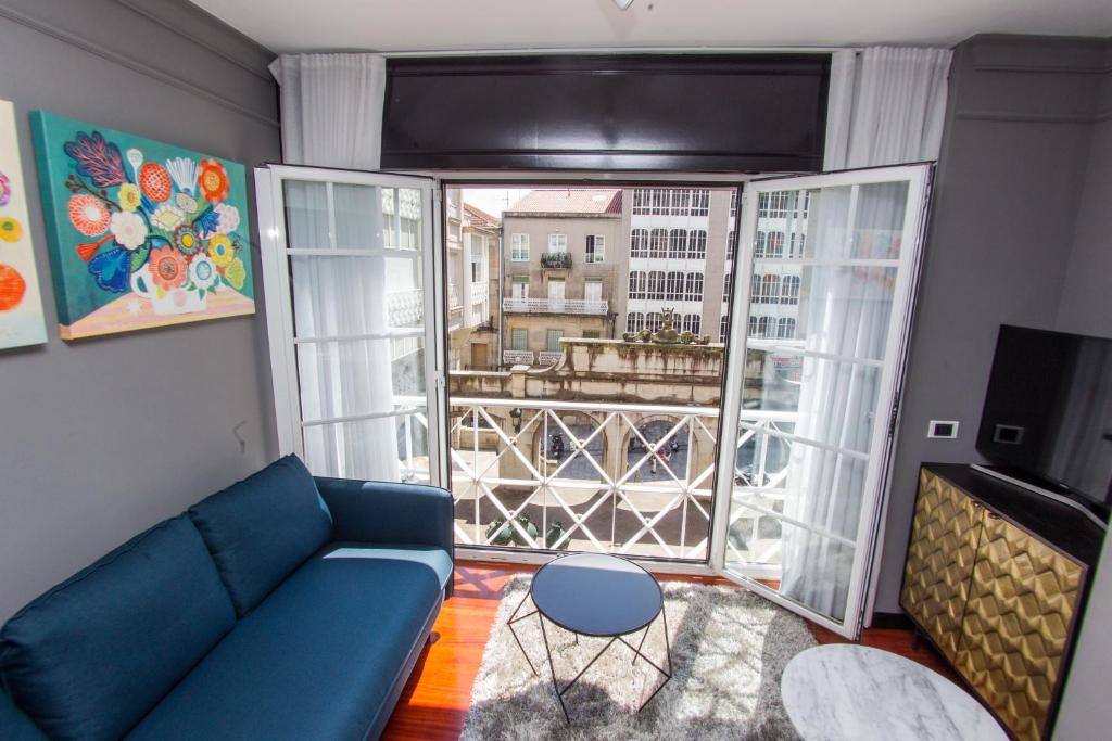 sala de estar con sofá azul y ventana grande en SUITE DE LUJO-CENTRO Kilometro 0-PARKING, en Vigo