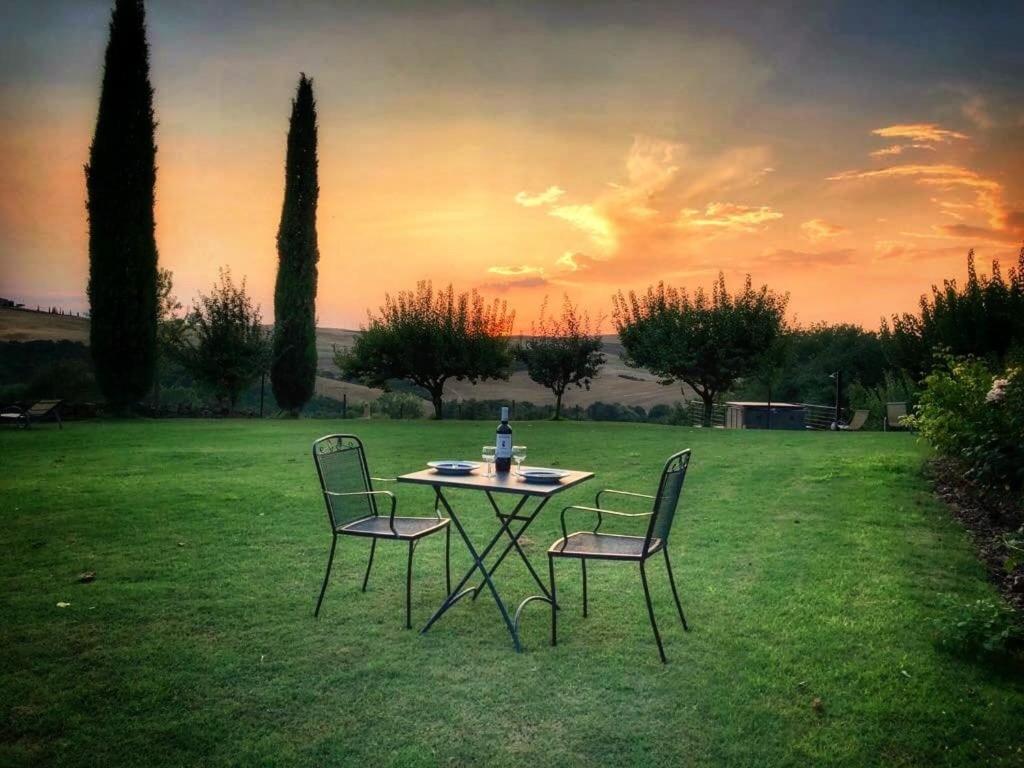 una mesa con dos sillas y una botella en un campo en Agriturismo Bagnolo, en Pienza