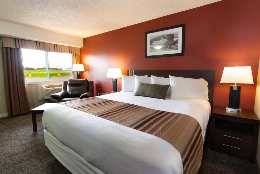 a hotel room with a large bed and a chair at BCMInns - Lloydminster in Lloydminster