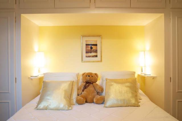 a teddy bear sitting on a bed with two pillows at 2 bedrooms apartment with free parking in Lancing