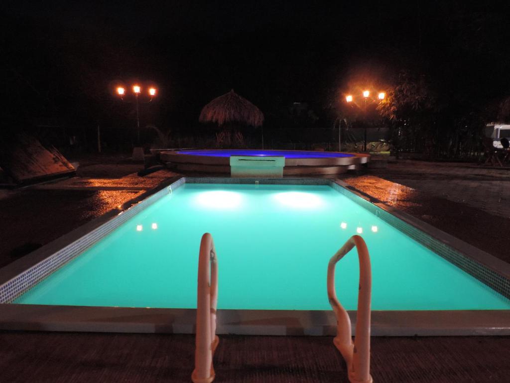 a swimming pool lit up at night at Hostal Villas Mexico in San Juan del Sur