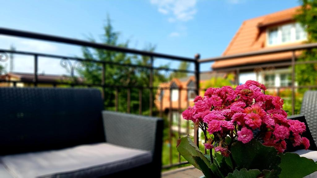 un jarrón de flores rosas sentado en una mesa en Apartament Lawenda, en Łeba