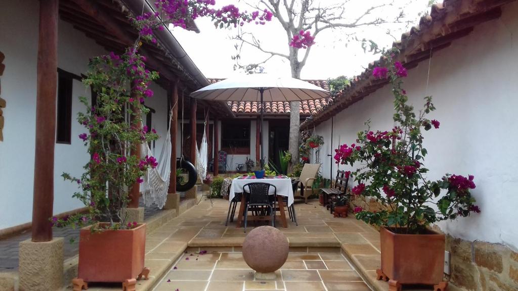 - une terrasse avec une table, des fleurs et un parasol dans l'établissement Casa Tierrarte, à Barichara