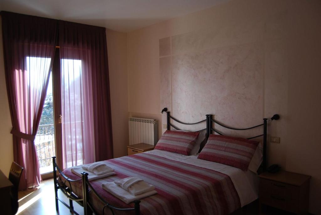 a bedroom with a bed with two pillows and a window at Hotel Iscla in Edolo