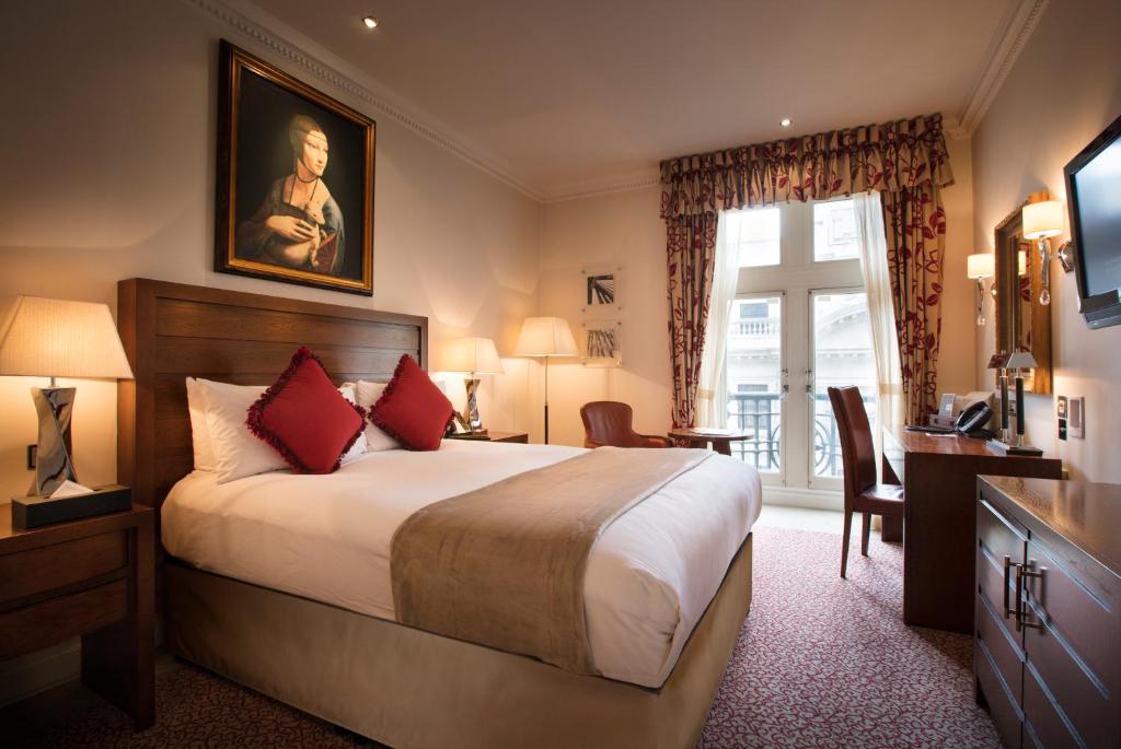 una camera d'albergo con letto, scrivania e finestra di The Royal Horseguards Hotel, London a Londra