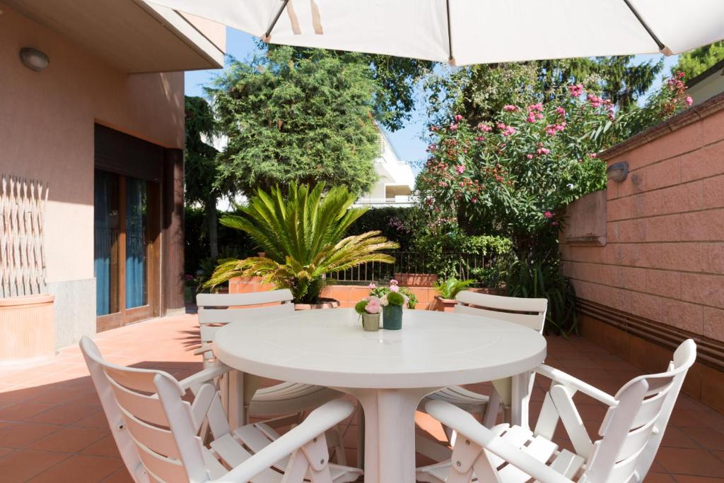 un tavolo bianco e sedie su un patio con ombrellone di B&B La Quercia a Pescara