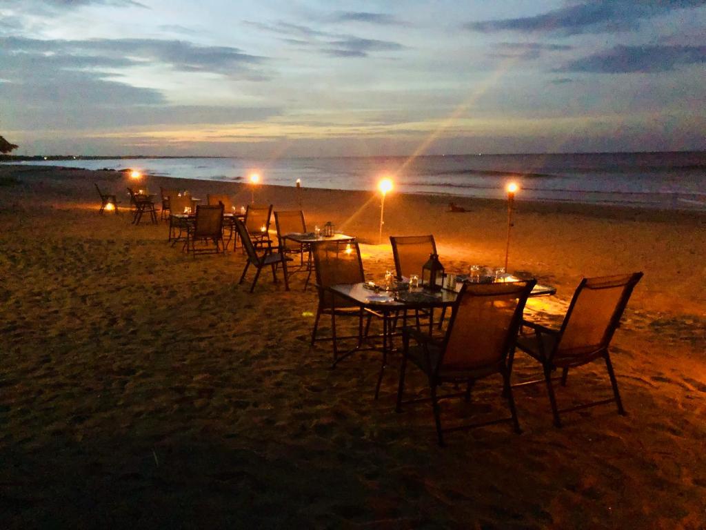 a group of tables and chairs on the beach at night at C Beyond Nilaveli in Nilaveli
