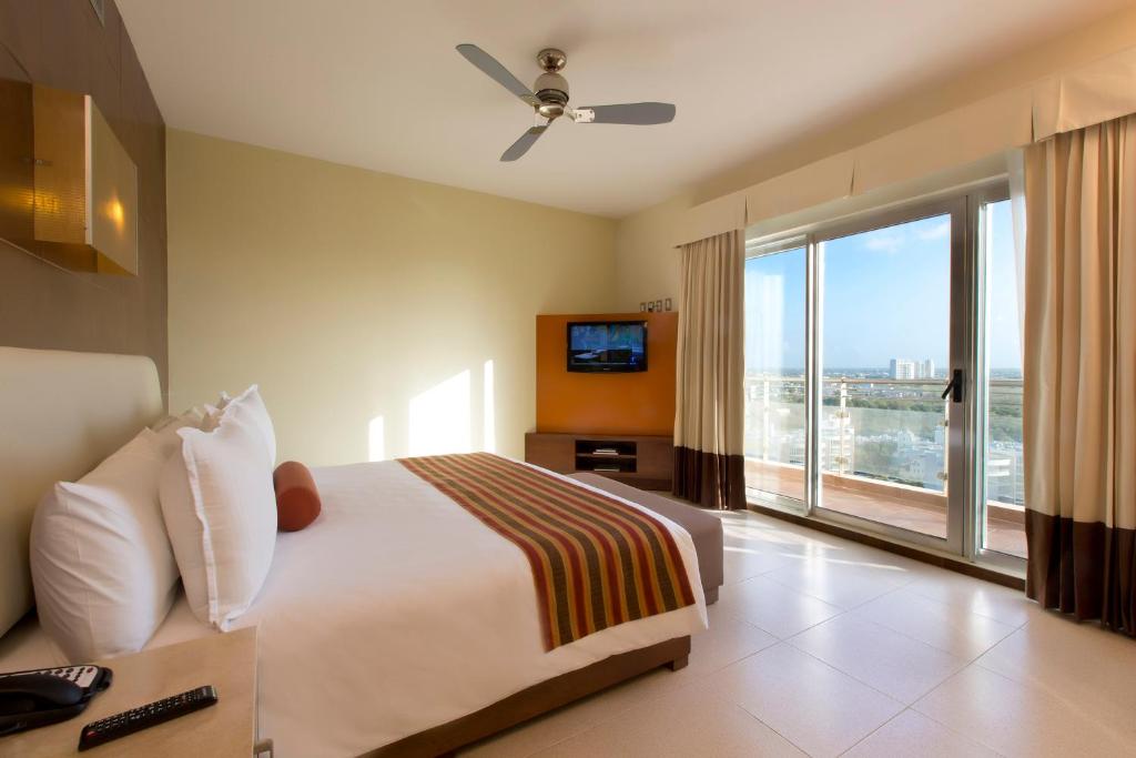 Cette chambre comprend un lit et une grande fenêtre. dans l'établissement Krystal Urban Cancun & Beach Club, à Cancún