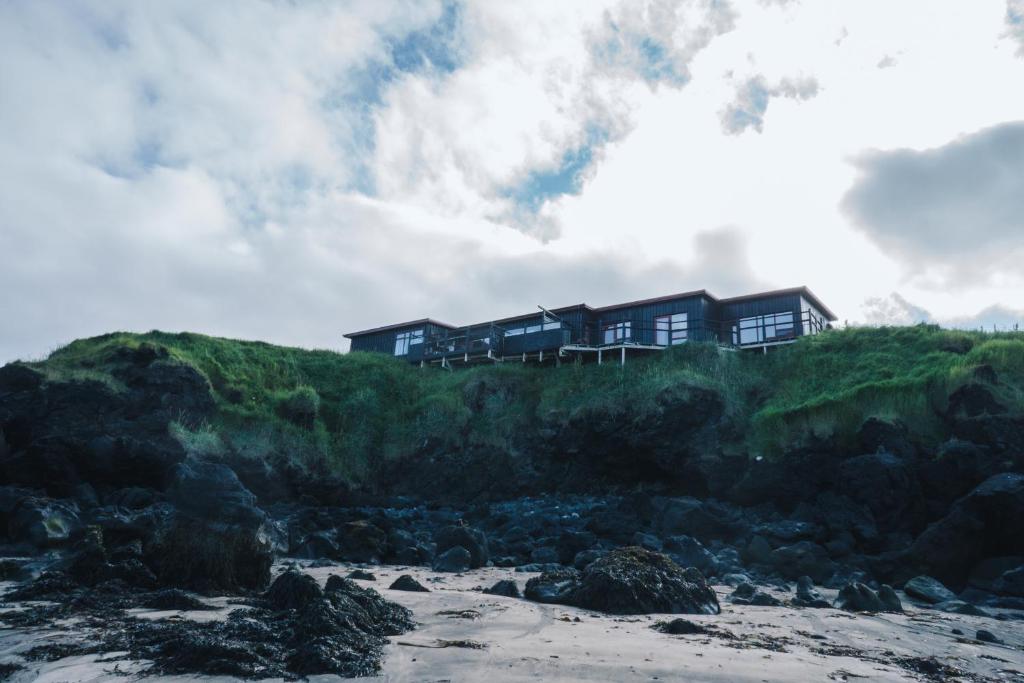 a house on top of a hill next to a beach at Brenna: Cliffside Apartment in Hellissandur