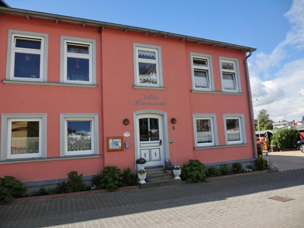 a red building with a white door on a street at Villa Harmonie in Lohme