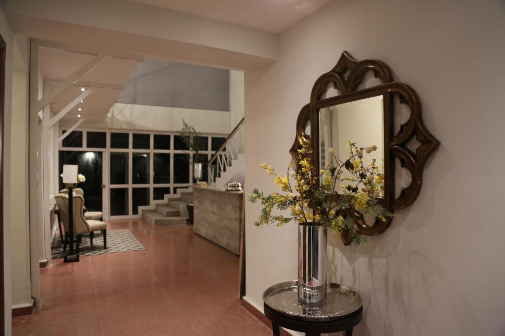 sala de estar con espejo y jarrón con flores en Casa Massima Hotel en León