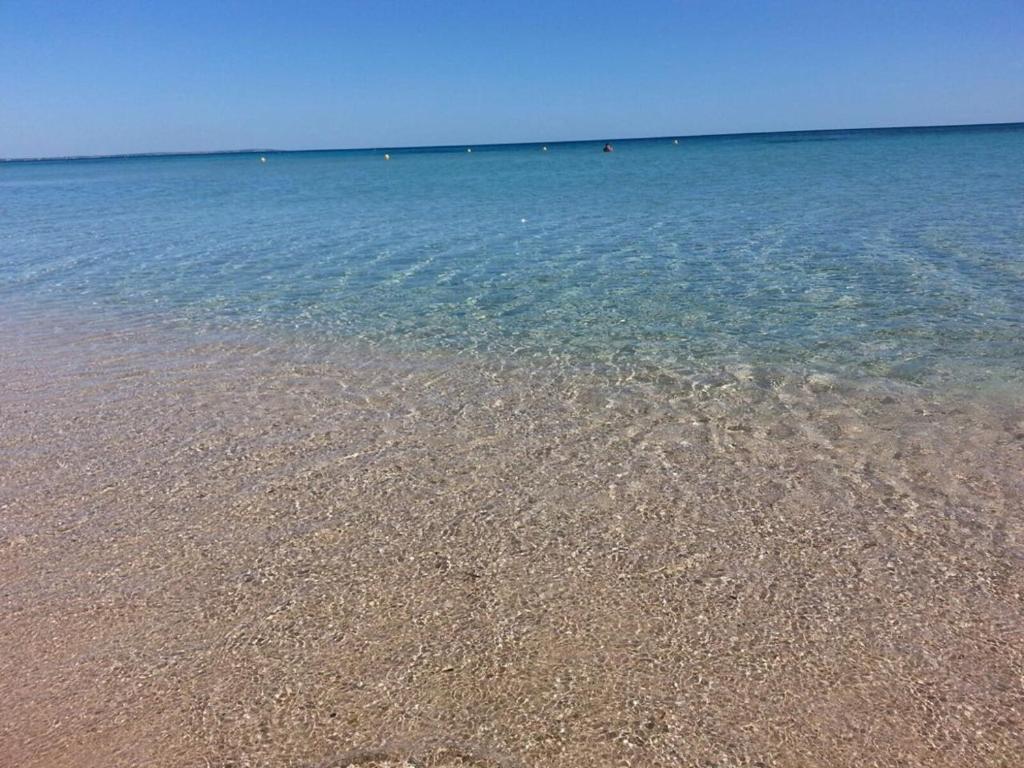 una playa con agua azul clara en un día claro en Tenuta Nonno Carmine, en Porto Cesareo
