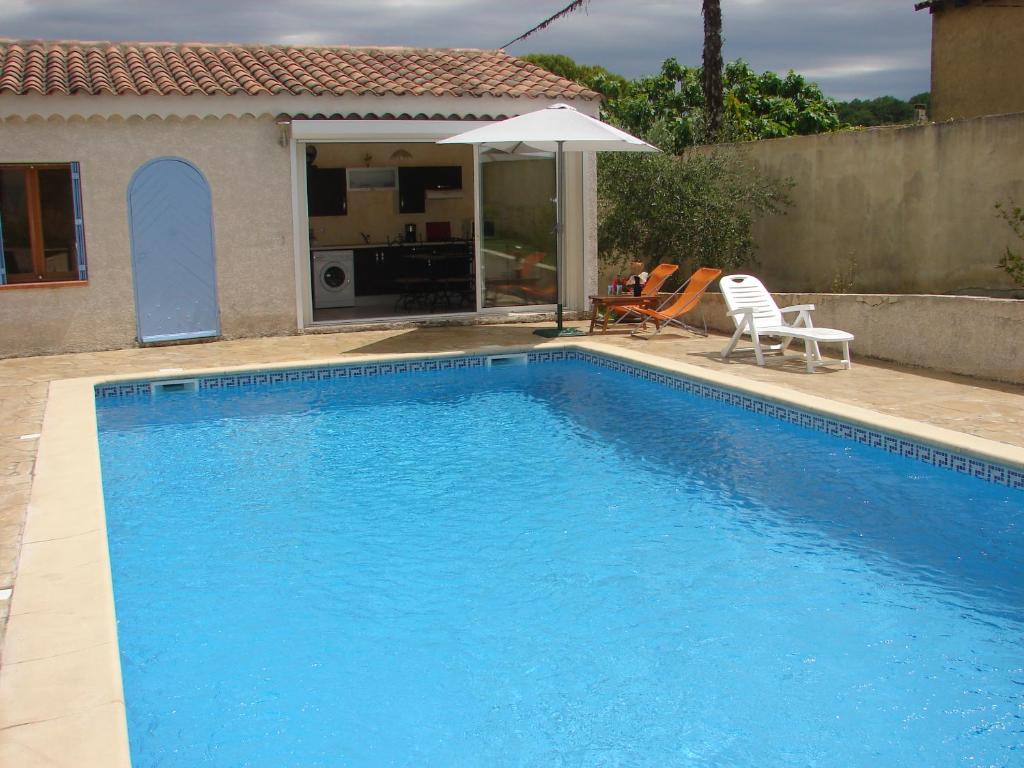 - une piscine bleue avec une chaise et un parasol dans l'établissement Gite les Bleuets, à Saze