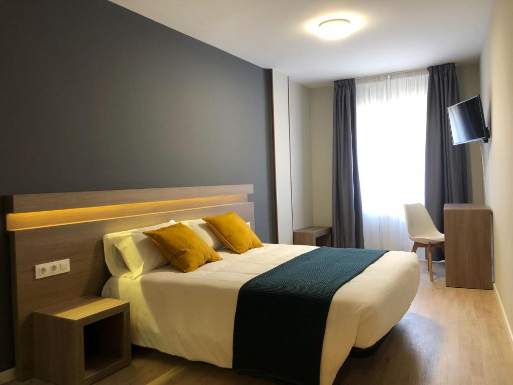 Un dormitorio con una cama con almohadas amarillas y una ventana. en Hotel Alda Estación Pontevedra, en Pontevedra