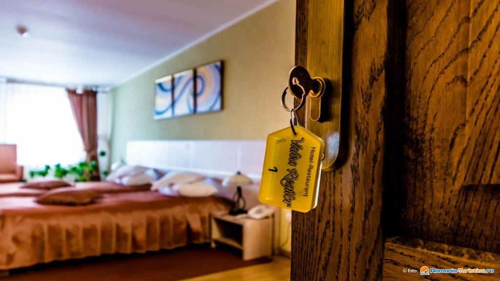 una etiqueta colgando de una puerta de madera con una cama en Valea Regilor Reghin en Reghin
