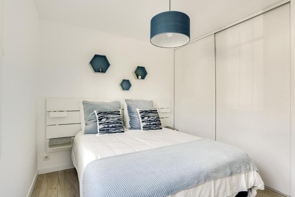 una camera bianca con letto e cuscini blu di T2 Calme, Fonctionnel et Spacieux - proche PARIS a Chanteloup-les-Vignes