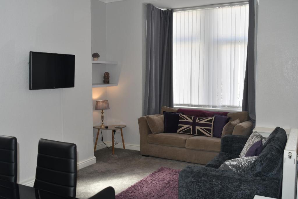 a living room with a couch and a tv at Adelaide Apartments in Blackpool