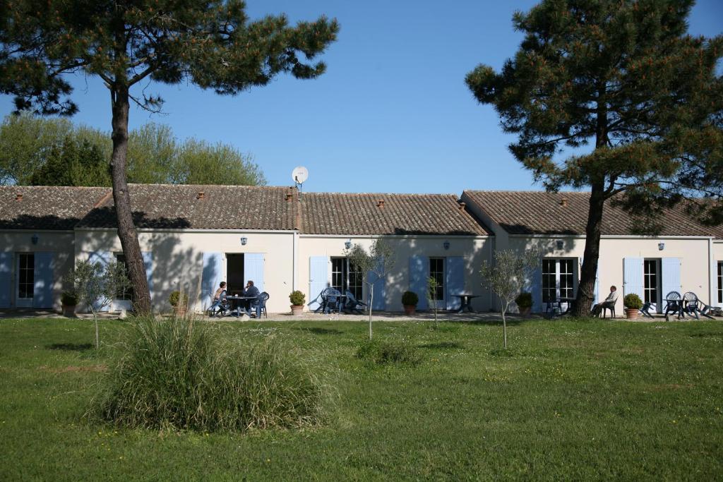een wit huis met mensen in een tuin bij Hotel Residence Les Alizes in Grand-Village-Plage