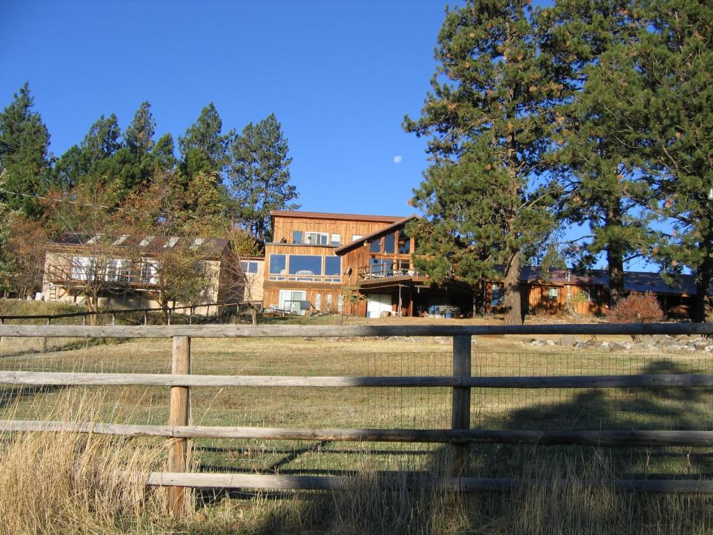 una casa en medio de un campo con una valla en Whitebird Summit Lodge, en Grangeville