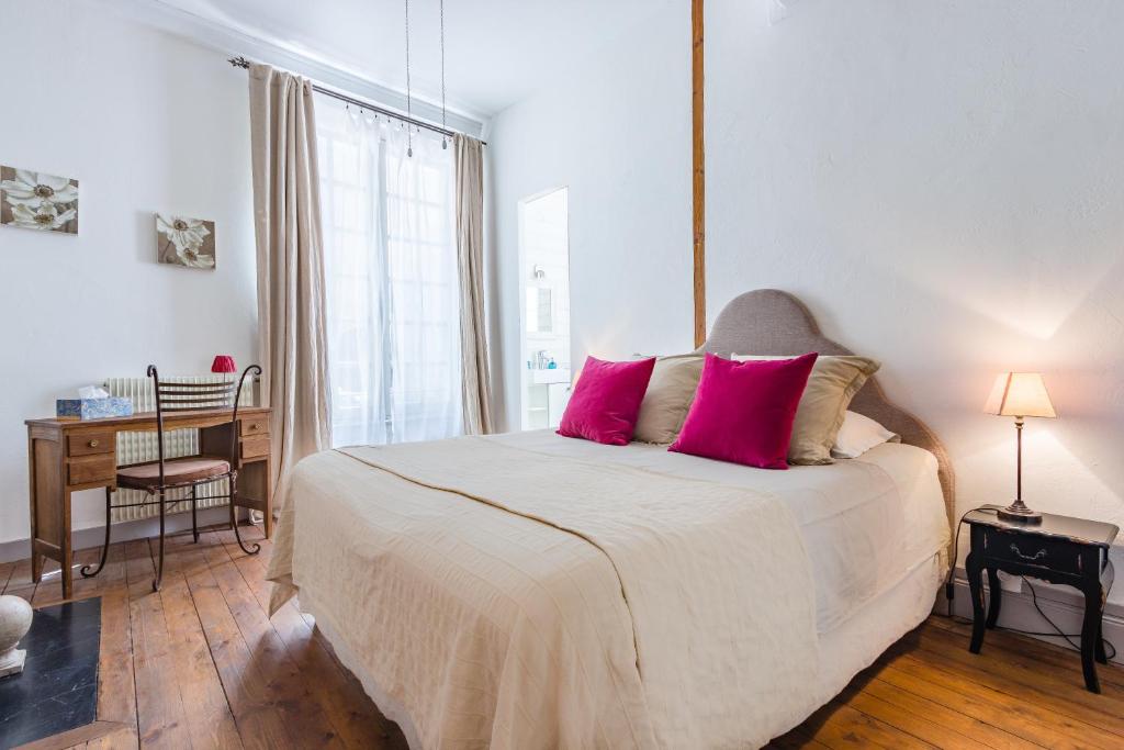 - une chambre avec un lit avec des oreillers roses et un bureau dans l'établissement VillaConcorde, à Amboise