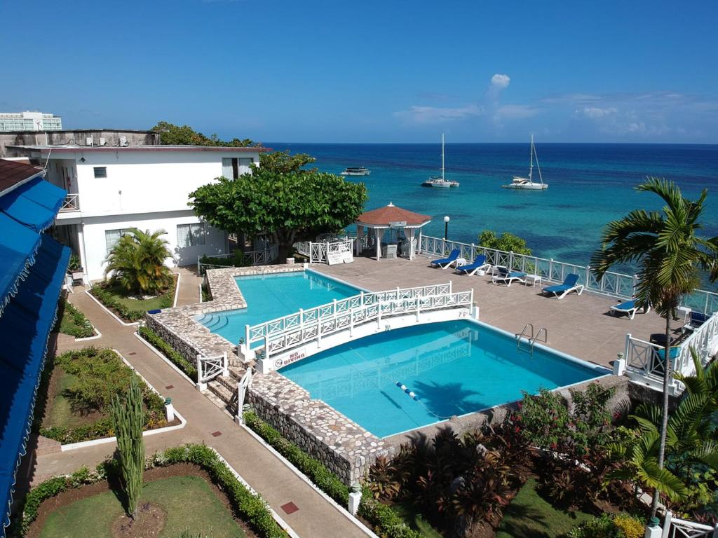 an aerial view of a swimming pool and the ocean at Hibiscus Lodge Hotel in Ocho Rios