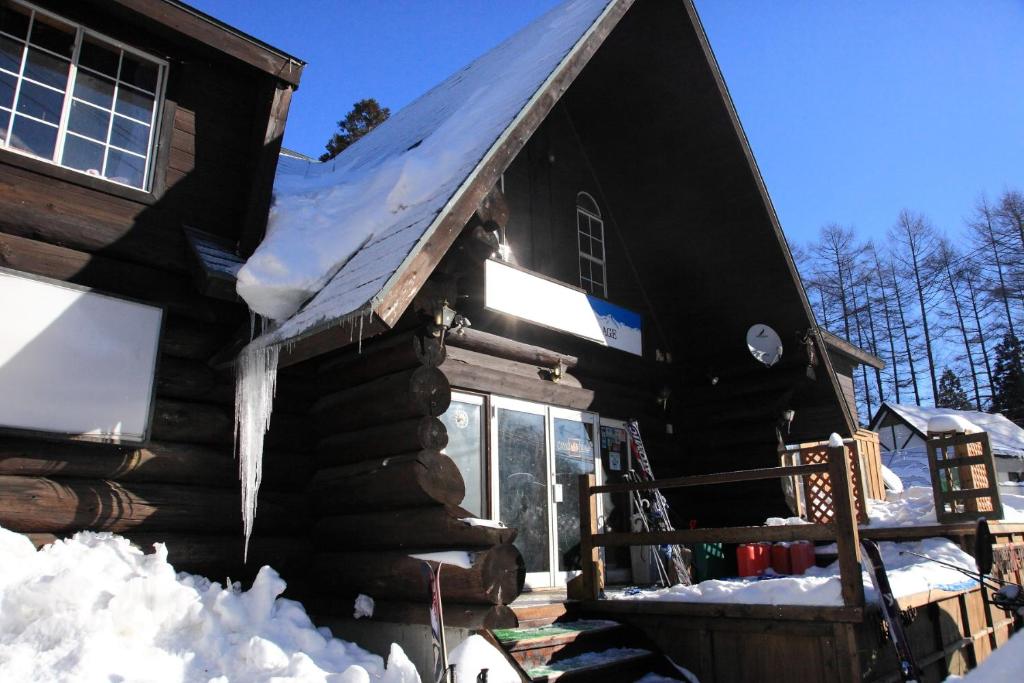 eine Blockhütte mit Schnee auf dem Dach in der Unterkunft Canadian Village Goryu in Hakuba