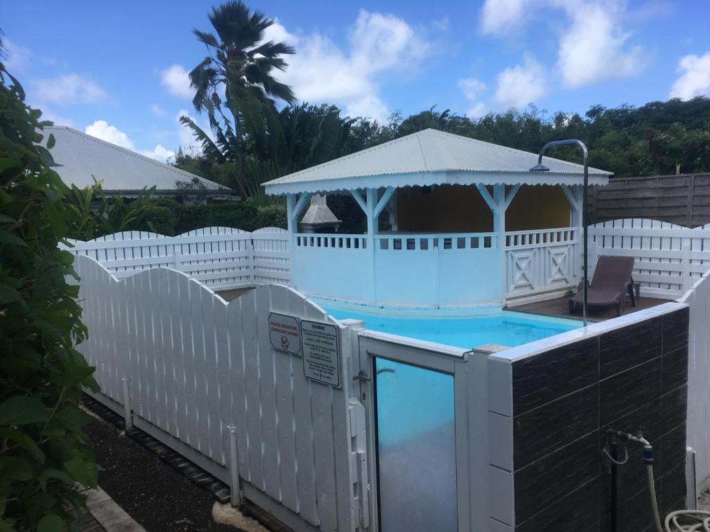 a white fence around a pool with a gazebo at Bungalow Takaya Bambou in Saint-François