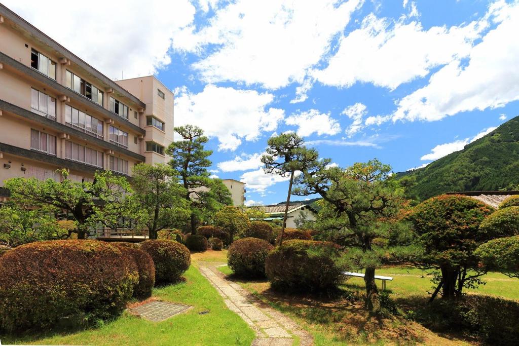 下呂的住宿－望川館，公园里建有一座建筑,还有一些灌木和树木