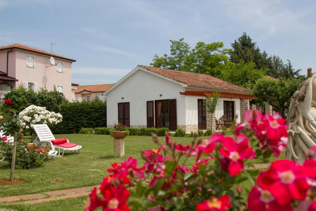 ein weißes Haus mit roten Blumen im Hof in der Unterkunft Holiday Home Linet in Funtana