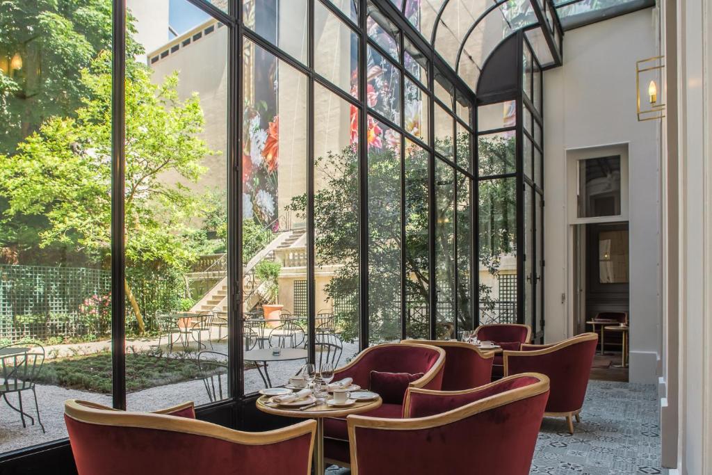 a restaurant with chairs and tables and a large window at Hôtel Alfred Sommier in Paris