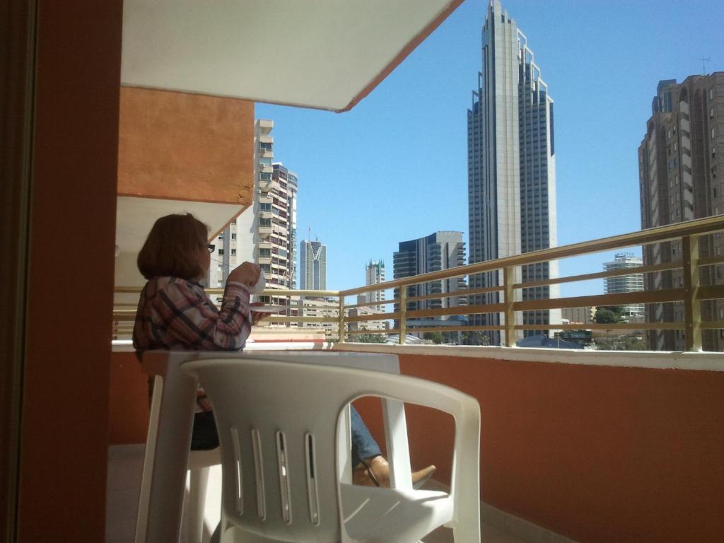 a woman sitting in a chair on a balcony at Apartamentos Ocaña in Cala de Finestrat