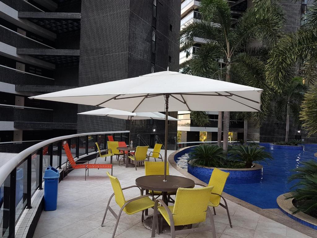 a table and chairs with an umbrella and a pool at Landscape Beira mar in Fortaleza