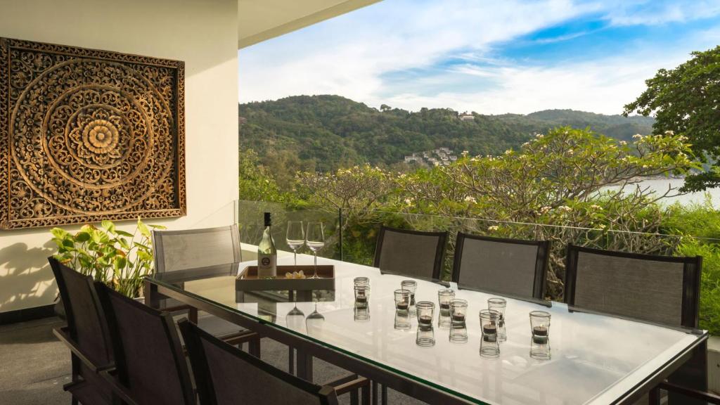 a table with wine glasses on a balcony with a view at Villa Princess Stephanie in Kata Beach