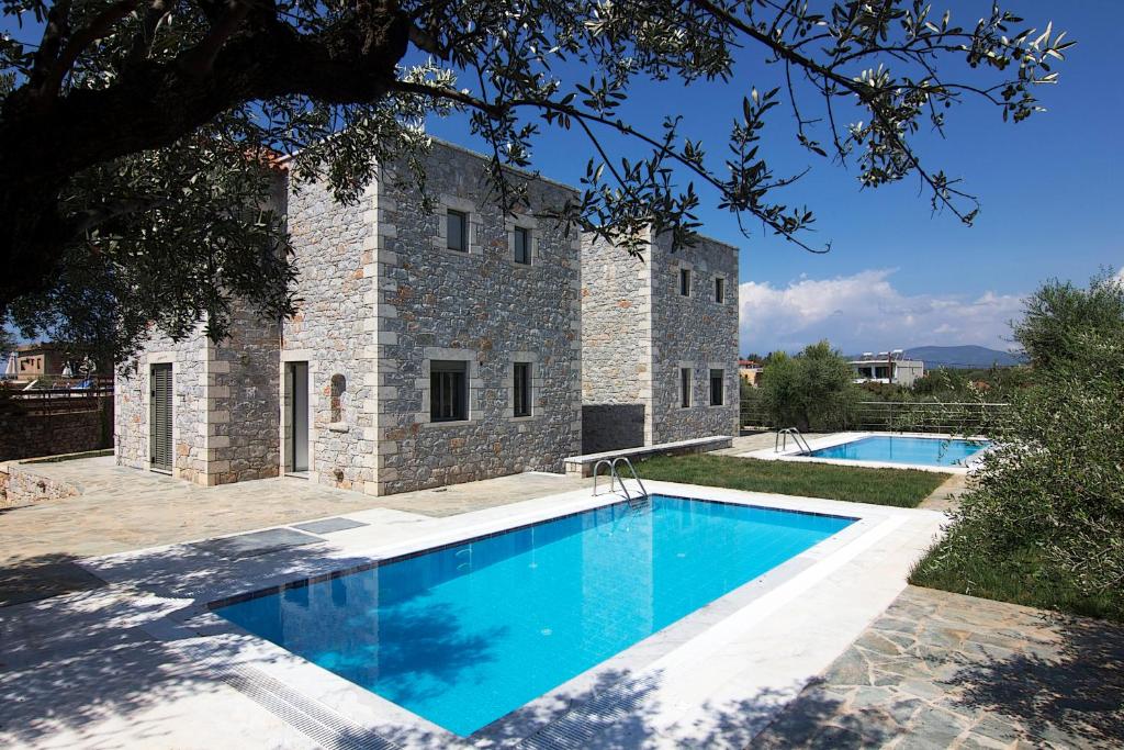 a villa with a swimming pool in front of a building at Torri di pietra in Stoupa
