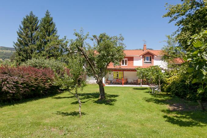 uma casa com um jardim verde com uma árvore em La Torrentera de Cantabria em Rada