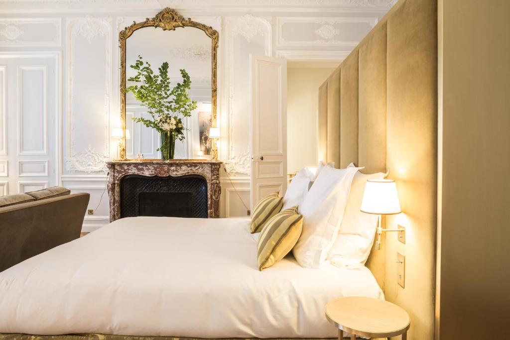 a bedroom with a white bed and a mirror at Hôtel Alfred Sommier in Paris