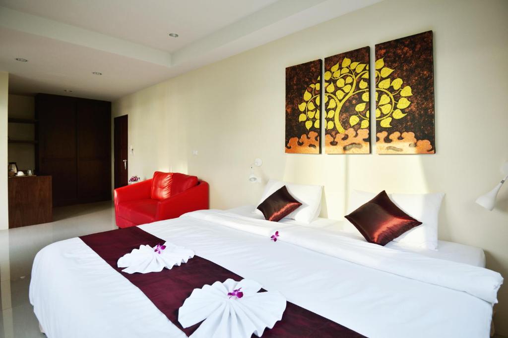 una camera d'albergo con due letti e una sedia rossa di At Kamala Hotel a Kamala Beach