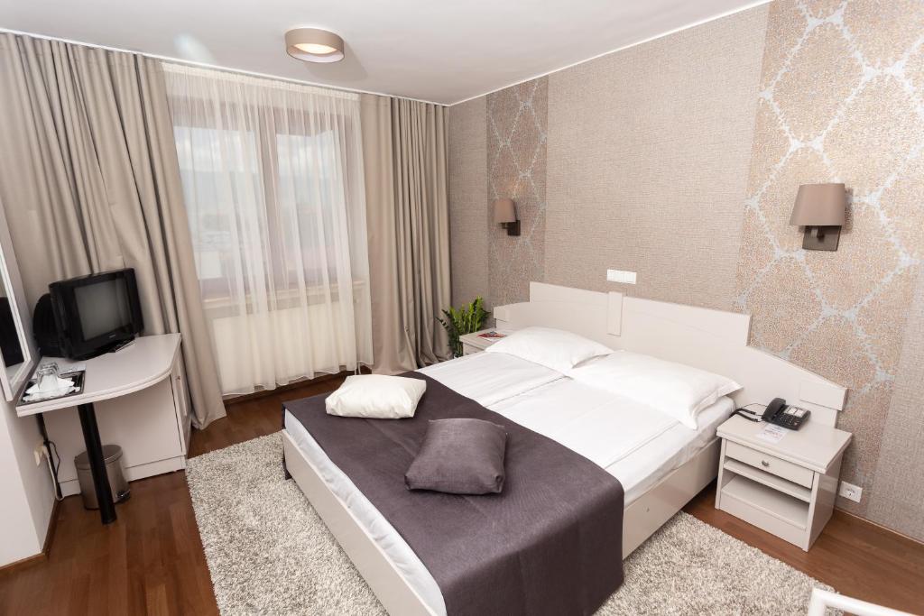 a bedroom with a large white bed and a television at Hotel Fenyõ in Miercurea-Ciuc