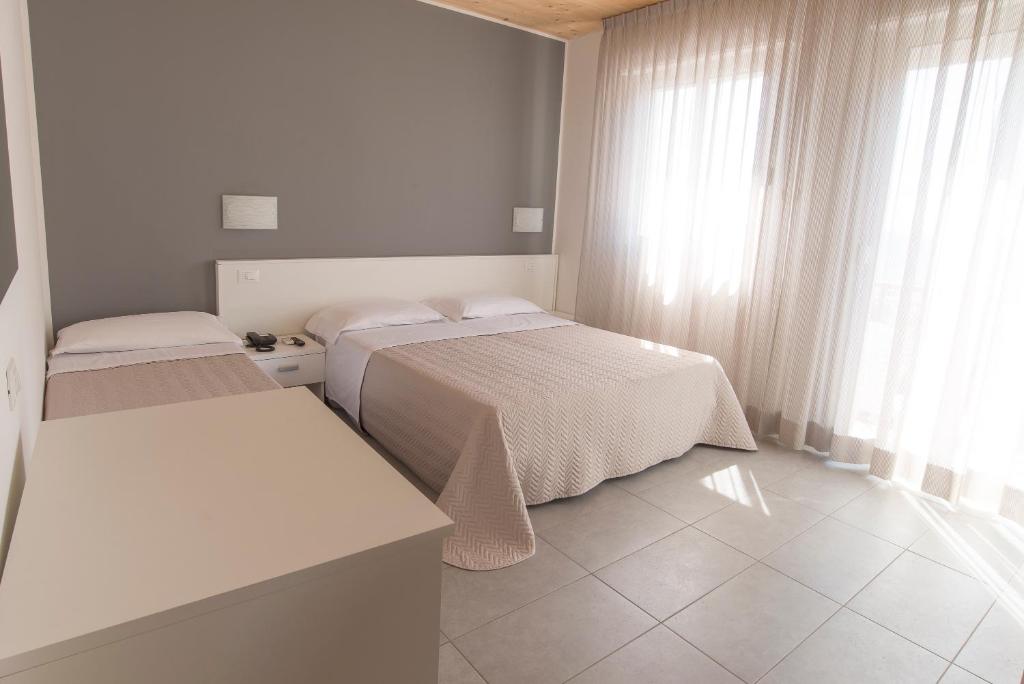 Habitación pequeña con 2 camas y ventana en Hotel Atene, en Lido di Jesolo
