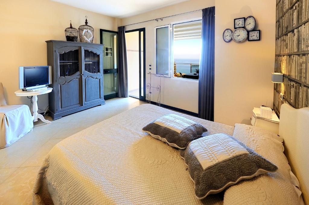 een slaapkamer met een groot bed en een televisie bij Poggio dei Gorleri in Diano Marina