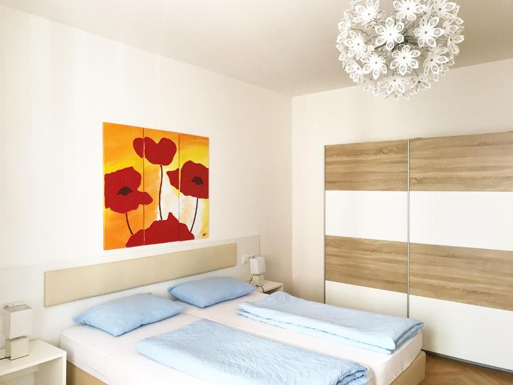 1 dormitorio con 1 cama con una pintura y una lámpara de araña en Rosengarten Apartments, en Bolzano