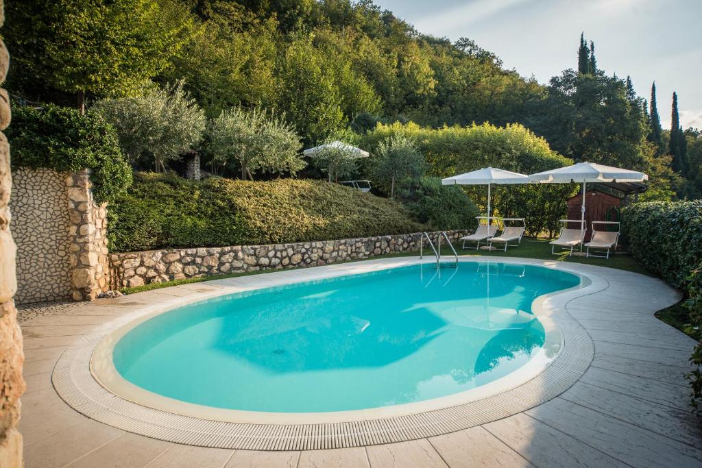 einen Pool in einem Garten mit Stühlen und Sonnenschirmen in der Unterkunft B&B La Rubiana in Caprino Veronese