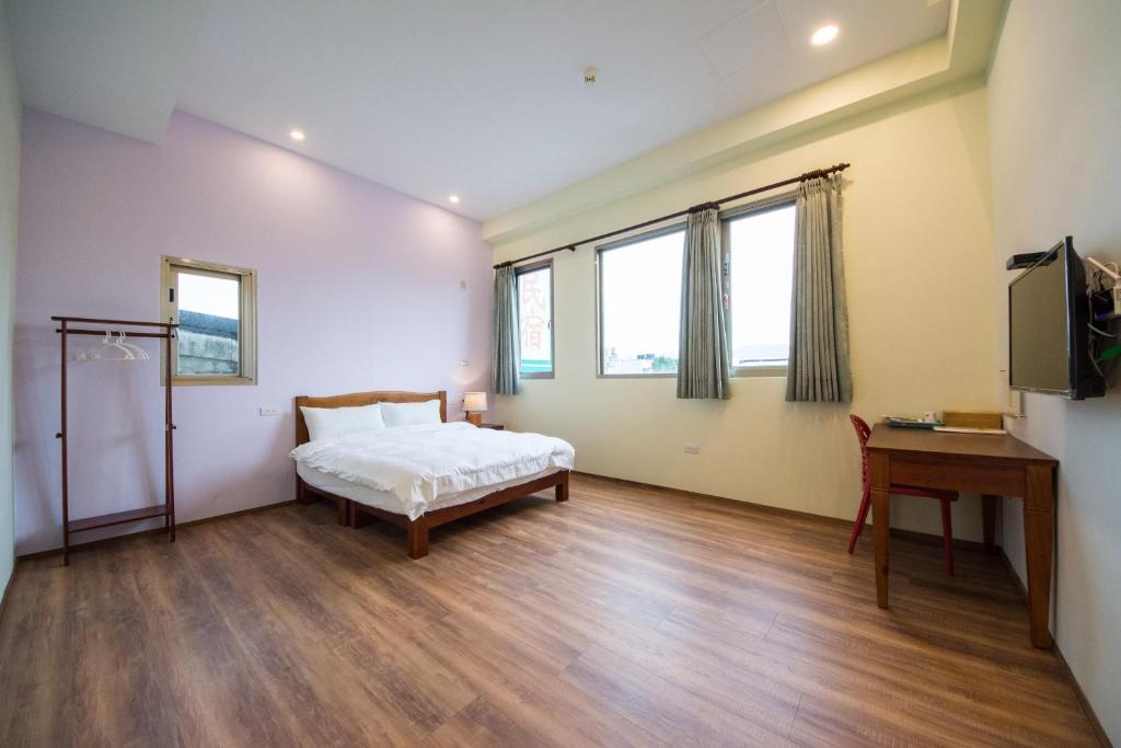 a bedroom with a bed and a desk and two windows at 7-113 hotel in Shoufeng