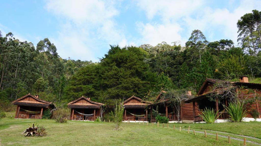 a group of huts in a field with trees at Pousada Cabanas da Serra Lumiar in Lumiar