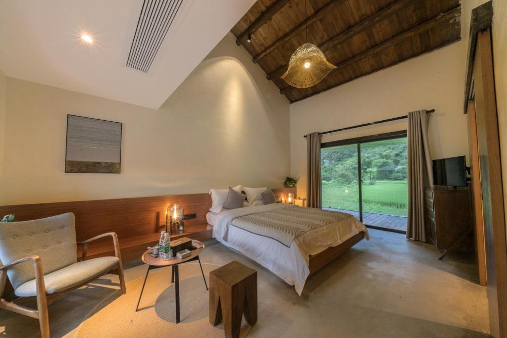 Un dormitorio con una cama, un sofá y una mesa. en 桂林阳朔万相青谷酒店Vision Villa Yangshuo, en Yangshuo
