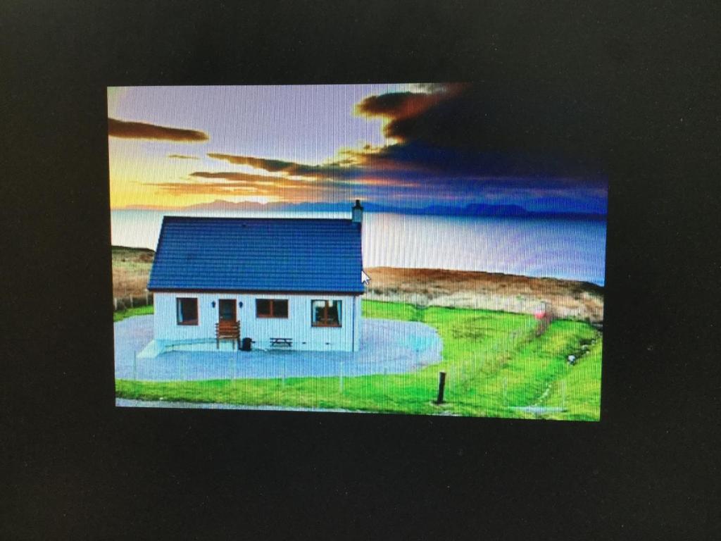 a small white house with a blue roof next to the water at Rona in Aultgrishin