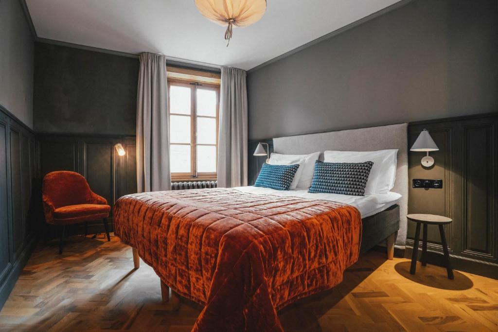 a bedroom with a bed and a chair and a window at Langley Hotel Gustavia in Chamonix