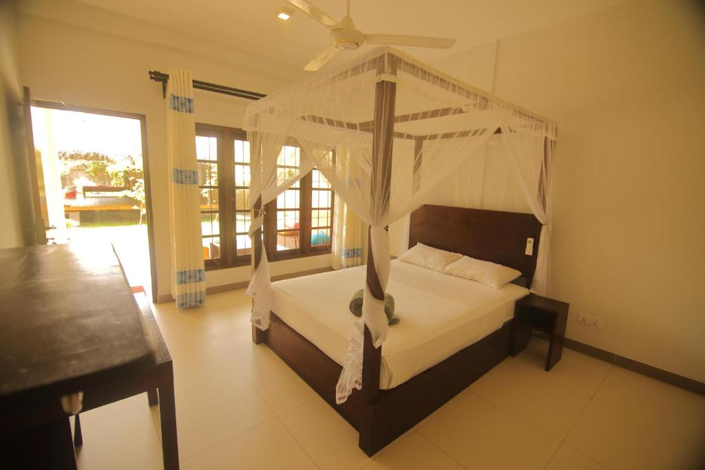 a bedroom with a canopy bed with a ceiling fan at JJ's Hostel Mirissa in Mirissa