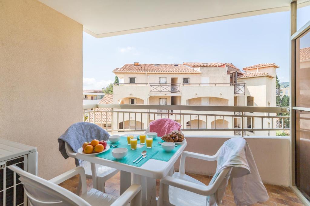 - un balcon avec une table et des chaises avec de la nourriture dans l'établissement Résidence Pierre & Vacances Les Platanes, à Sainte-Maxime