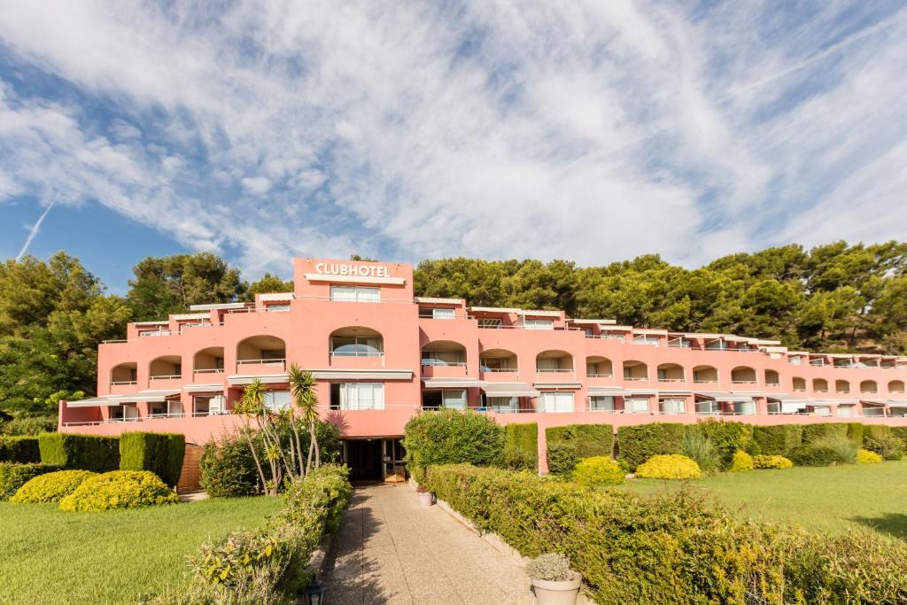 un edificio rosa con arbustos delante de él en Résidence Pierre & Vacances Les Jardins de la Côte d'Azur en Saint-Mandrier-sur-Mer